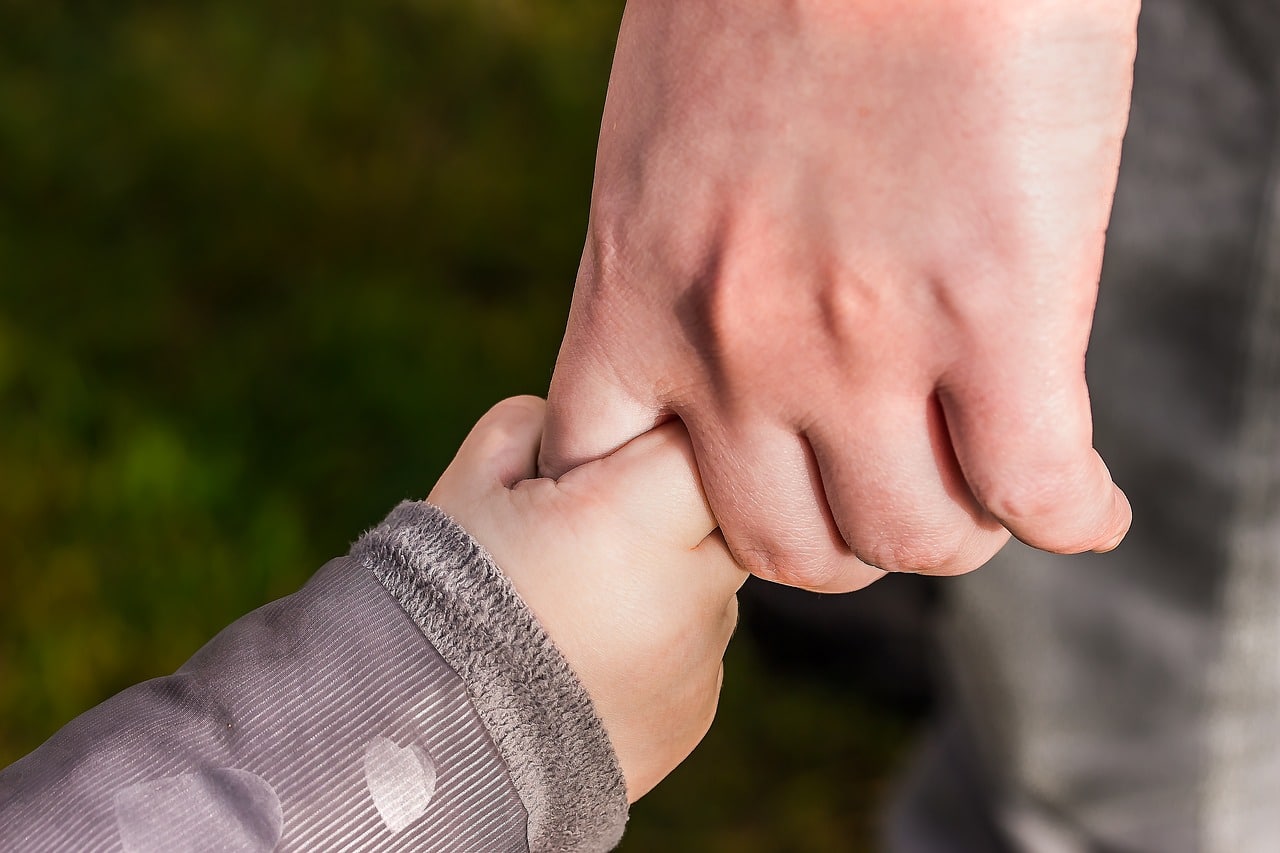 enfant tenant la main d'un adulte